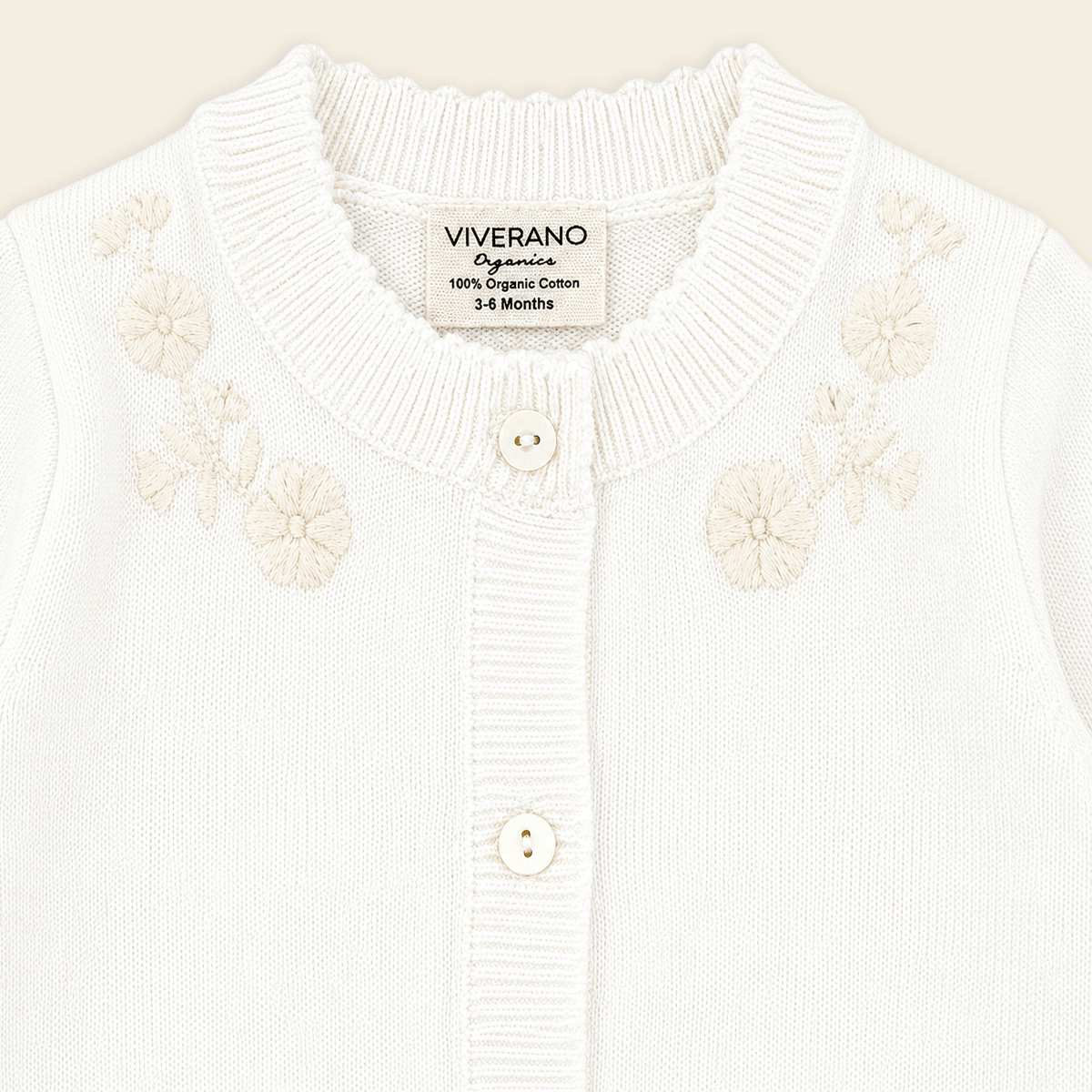 close up of dove white floral embroidered knit baby jumpsuit made with organic cotton