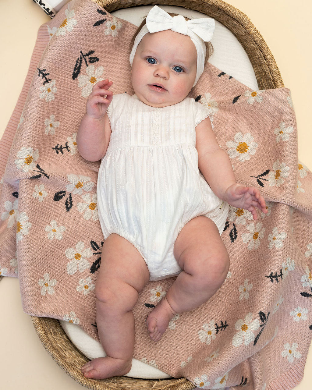 Daisy Floral - Jacquard Sweater Knit Baby Blanket (Organic Cotton) with model wearing Darie Striped Dobby Romper & Headband Set
