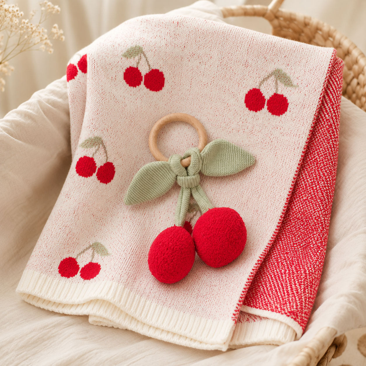Cherry Organic Baby Blanket + Ring Rattle Toy Gift Set on a chair