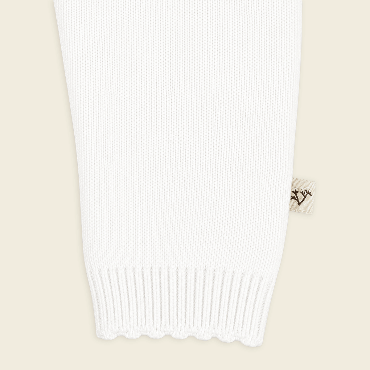 close up of sleeve  from milan dove white delicate pointelle knit baby jumpsuit made with organic cotton